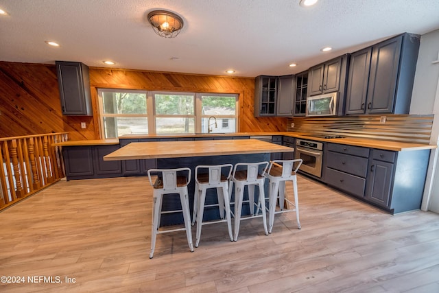 kitchen featuring wood counters, wood walls, a kitchen breakfast bar, a kitchen island, and stainless steel appliances