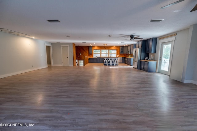 unfurnished living room with a textured ceiling, hardwood / wood-style flooring, and ceiling fan