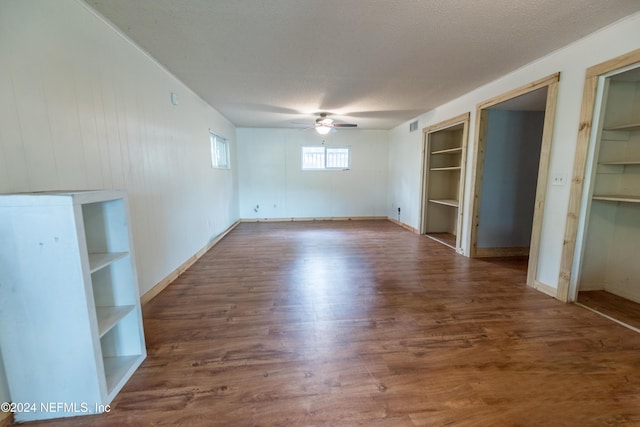 unfurnished bedroom featuring multiple closets, ceiling fan, dark hardwood / wood-style flooring, and a textured ceiling