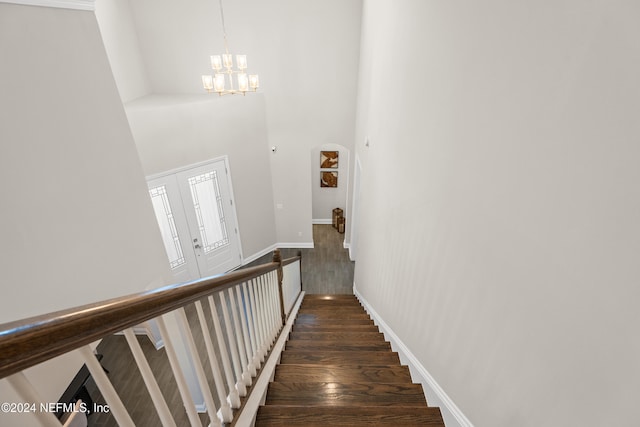 stairway featuring a high ceiling, hardwood / wood-style flooring, and an inviting chandelier