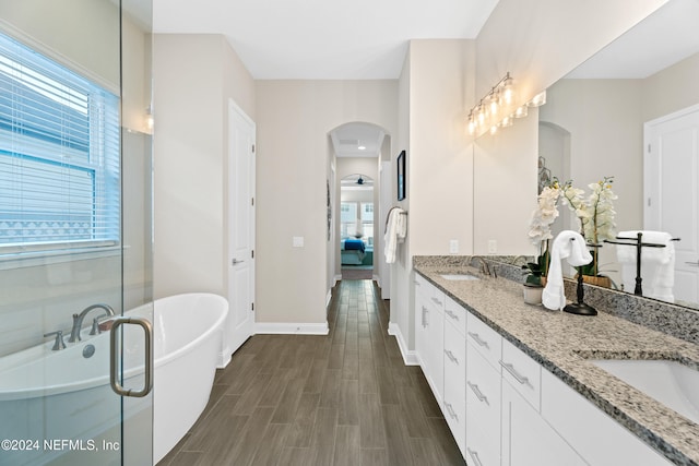 bathroom with a tub to relax in, hardwood / wood-style floors, and vanity