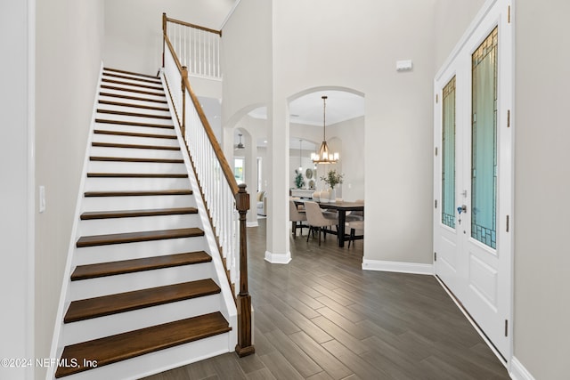 foyer entrance featuring dark wood-type flooring, french doors, ornamental molding, a towering ceiling, and a chandelier