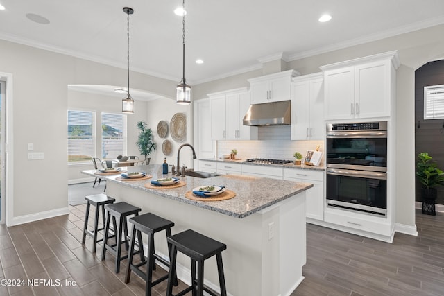 kitchen with stainless steel appliances, white cabinetry, a kitchen island with sink, and sink