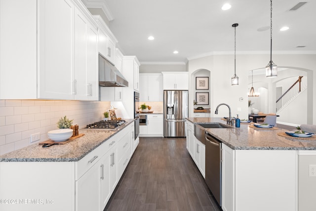 kitchen with white cabinets, pendant lighting, stainless steel appliances, and an island with sink