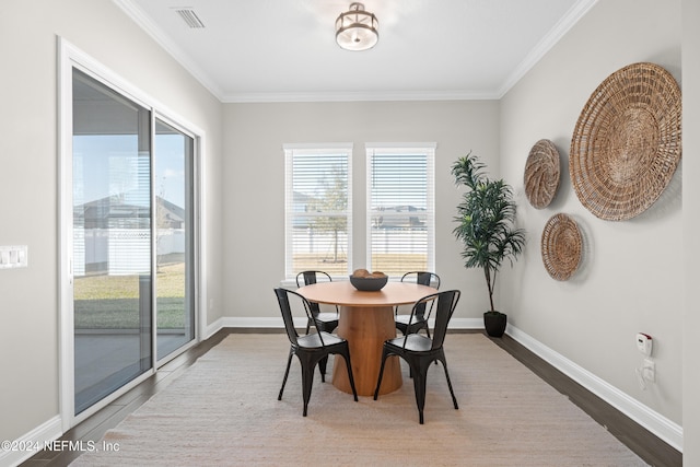 dining space with wood-type flooring, ornamental molding, and a wealth of natural light