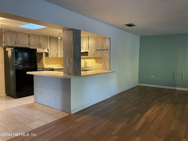 kitchen featuring sink, black fridge, light hardwood / wood-style flooring, kitchen peninsula, and light brown cabinetry