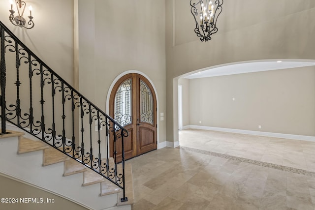 entrance foyer with a notable chandelier, light tile patterned flooring, a high ceiling, and french doors