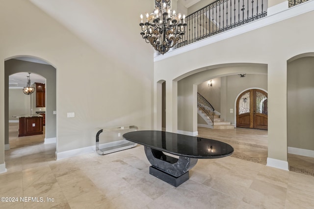 foyer with french doors, a towering ceiling, and a notable chandelier