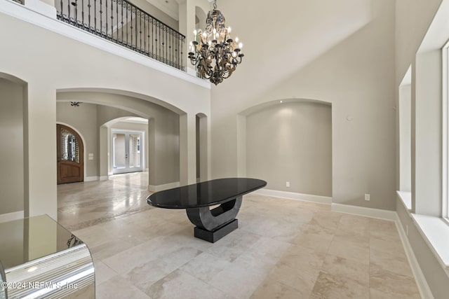 entryway featuring a towering ceiling, french doors, and a chandelier