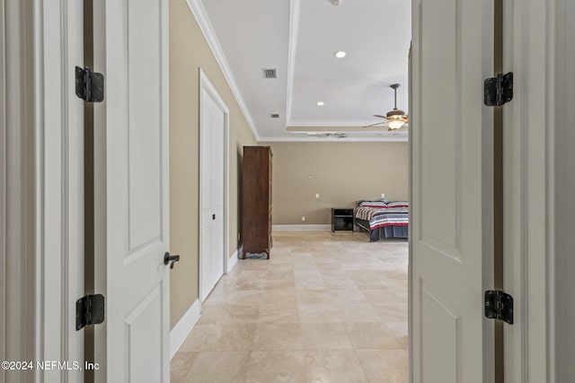 hallway with ornamental molding and a tray ceiling