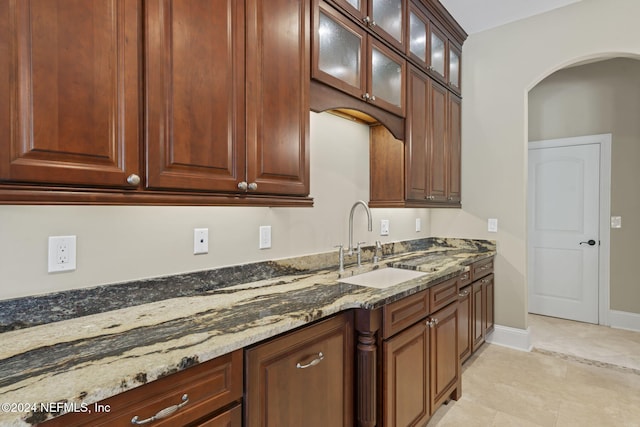 kitchen featuring dark stone countertops, sink, and light tile patterned floors