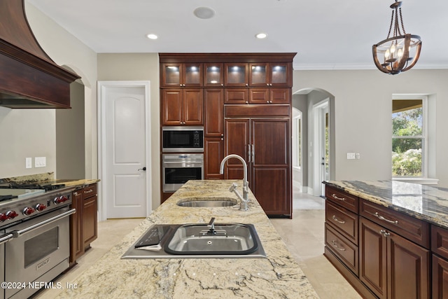 kitchen with crown molding, sink, hanging light fixtures, built in appliances, and light stone counters