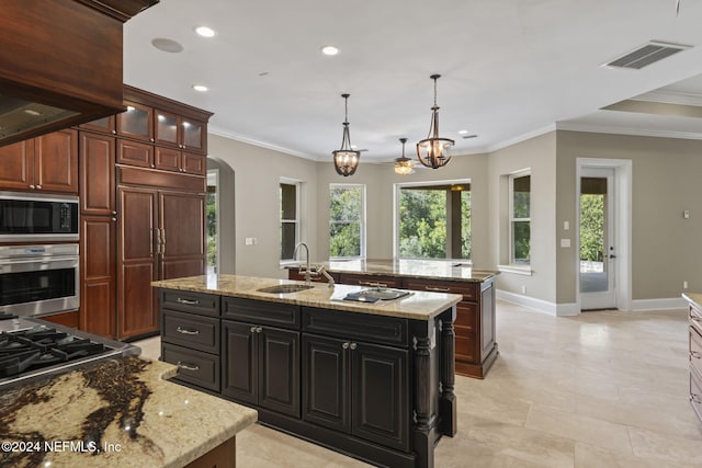 kitchen featuring built in appliances, a notable chandelier, sink, and an island with sink