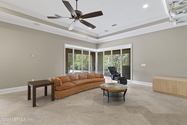 living room with a raised ceiling, ceiling fan, and ornamental molding