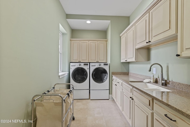 clothes washing area with cabinets, light tile patterned flooring, washing machine and clothes dryer, and sink