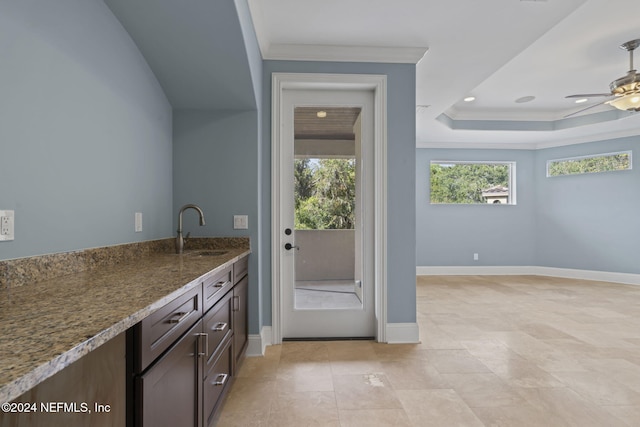 interior space featuring crown molding, sink, ceiling fan, and dark stone counters