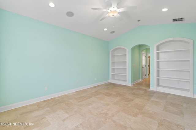 empty room with ceiling fan, built in features, and lofted ceiling