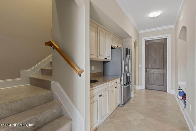 kitchen featuring cream cabinetry, stainless steel refrigerator with ice dispenser, and crown molding