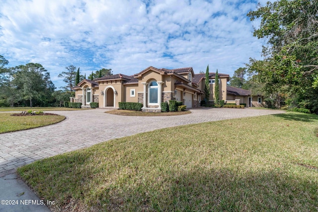 mediterranean / spanish-style home featuring a garage and a front lawn