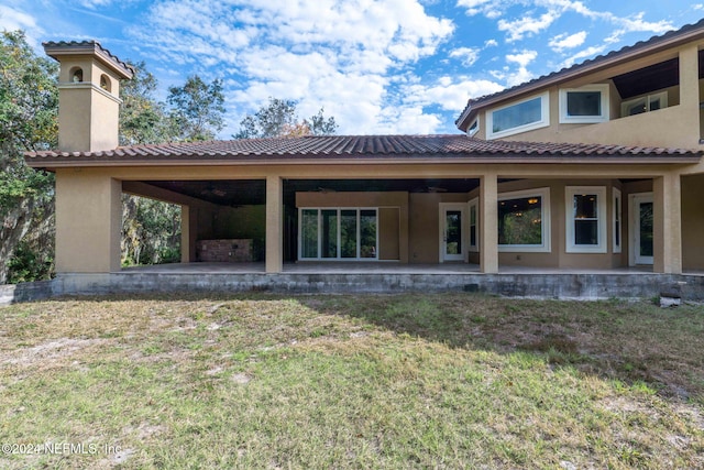 back of house with a patio area and a lawn