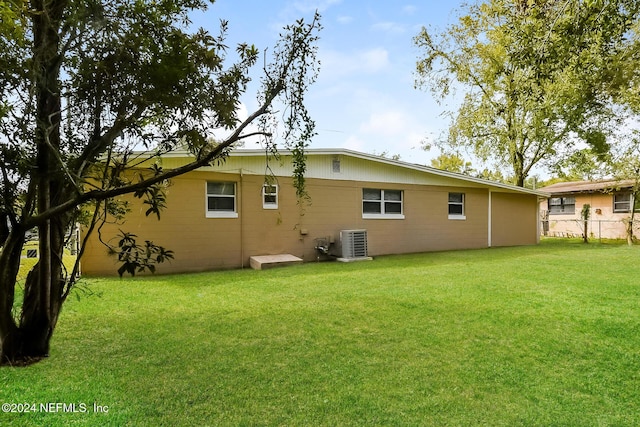 rear view of house featuring central AC and a lawn