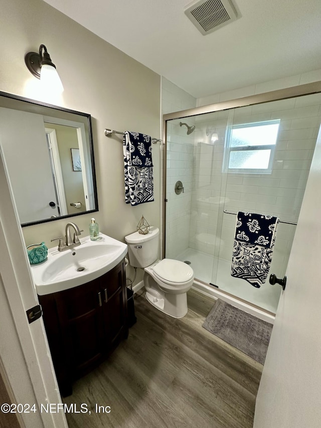 bathroom with toilet, vanity, a shower with door, and hardwood / wood-style flooring