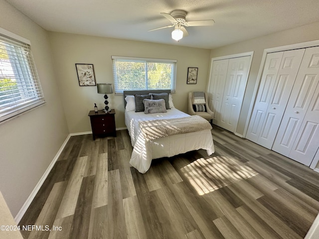 bedroom with ceiling fan, dark hardwood / wood-style flooring, and two closets