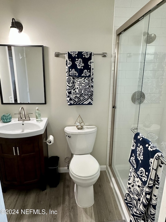 bathroom with toilet, wood-type flooring, an enclosed shower, and vanity