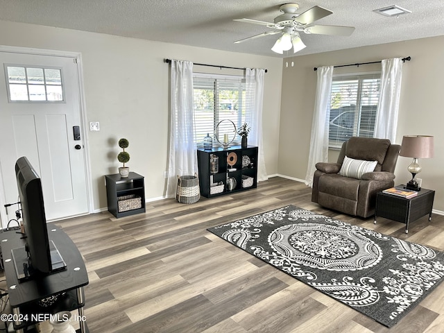 living room with ceiling fan, a textured ceiling, and hardwood / wood-style flooring