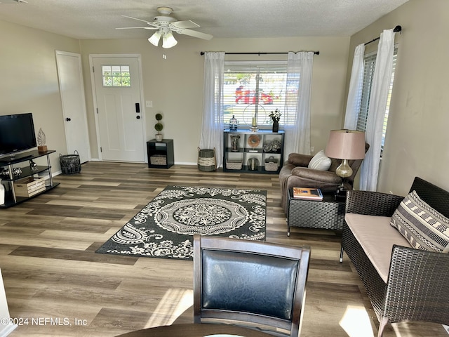 living room with ceiling fan, wood-type flooring, and a textured ceiling