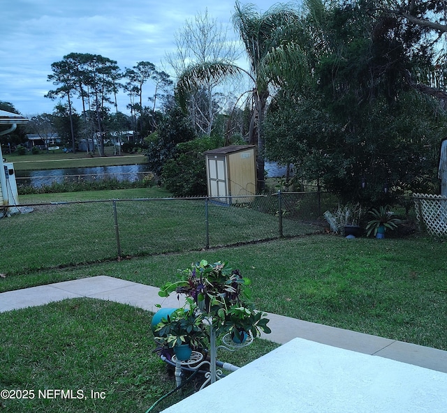 view of yard featuring a storage shed and a water view