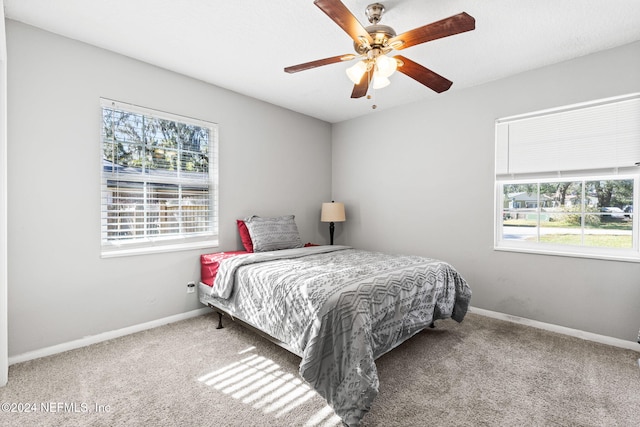 carpeted bedroom featuring ceiling fan and multiple windows