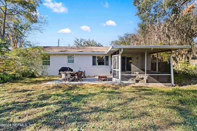 back of house featuring a sunroom, a patio, and a lawn