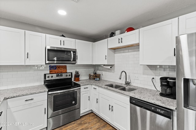 kitchen featuring sink, dark wood-type flooring, backsplash, white cabinets, and appliances with stainless steel finishes