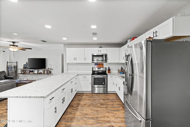 kitchen featuring white cabinets, dark hardwood / wood-style floors, decorative backsplash, appliances with stainless steel finishes, and kitchen peninsula