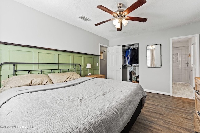 bedroom with a textured ceiling, ceiling fan, connected bathroom, dark hardwood / wood-style floors, and a closet