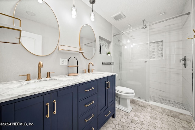 bathroom featuring a textured ceiling, vanity, a shower with door, tile patterned flooring, and toilet