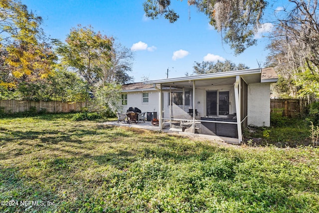 rear view of property with a sunroom, a patio area, and a yard