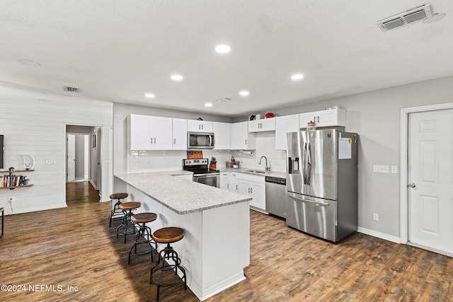 kitchen with white cabinets, stainless steel appliances, kitchen peninsula, and sink