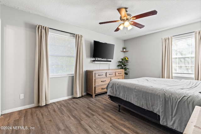 bedroom with a textured ceiling, ceiling fan, and dark wood-type flooring