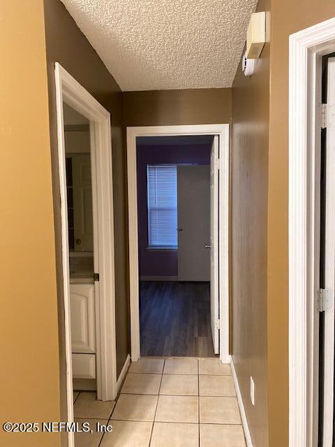 corridor featuring a textured ceiling and light tile patterned floors