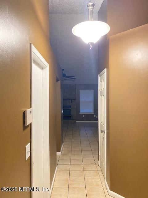 corridor featuring light tile patterned floors and a textured ceiling