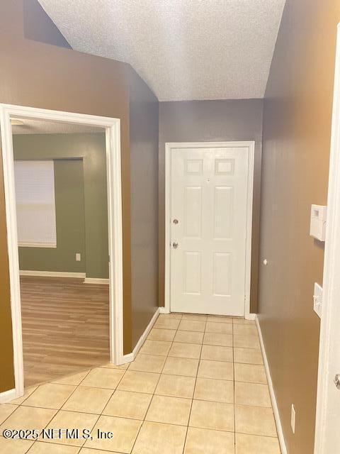 hall featuring a textured ceiling and light tile patterned floors