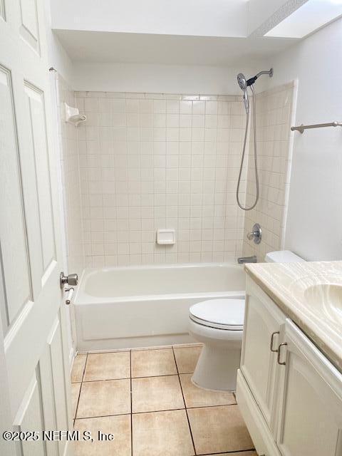 full bathroom featuring tile patterned flooring, vanity, tiled shower / bath combo, and toilet