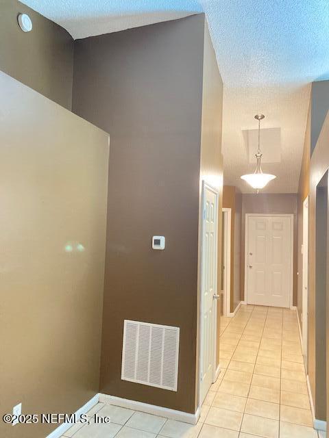 hall with light tile patterned flooring and a textured ceiling