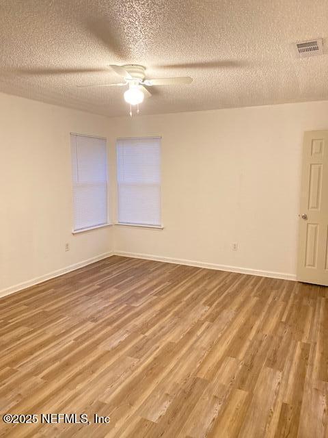 unfurnished room with hardwood / wood-style flooring, ceiling fan, and a textured ceiling