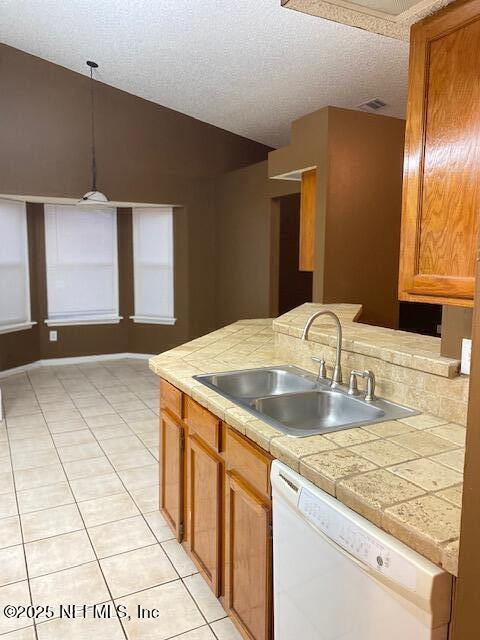 kitchen with vaulted ceiling, sink, hanging light fixtures, light tile patterned floors, and white dishwasher