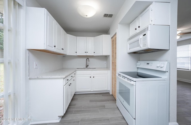 kitchen with light stone countertops, tasteful backsplash, white appliances, sink, and white cabinetry