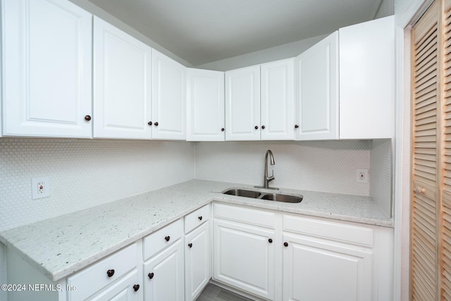 kitchen with white cabinets, light stone countertops, and sink