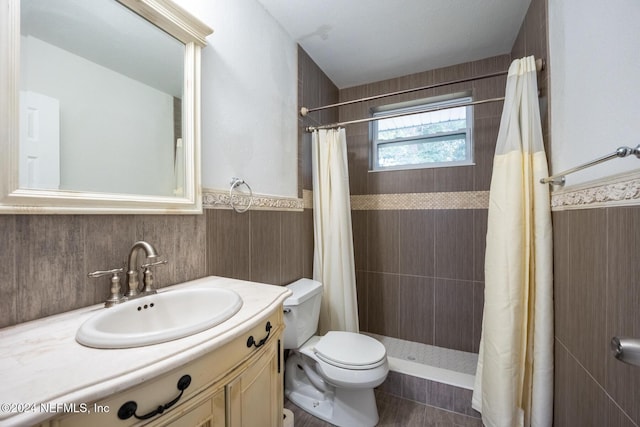 bathroom featuring vanity, toilet, curtained shower, and tile walls